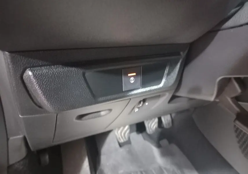 Gros plan sur le bouton de frein à main électrique dans l'habitacle noir d'une Dacia Sandero Extreme+ TCe 110 2024.