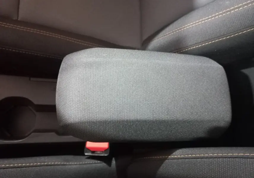 Accoudoir central en tissu gris avec coutures marron sur les sièges avant d'une Dacia Sandero 2024.