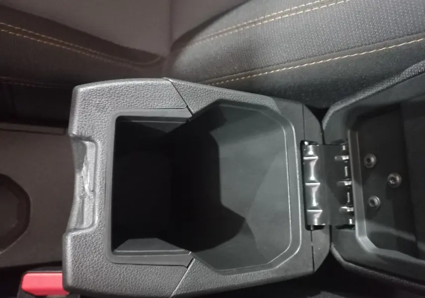 Gros plan sur le rangement central ouvert entre les sièges avant du Dacia Sandero 2024, tissu gris avec surpiqûres beiges.