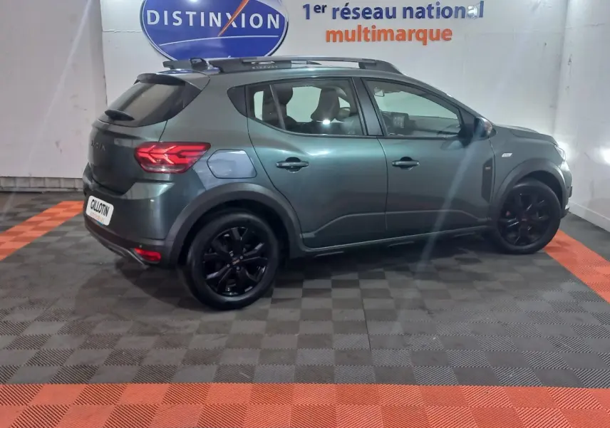 Vue de profil côté gauche d'une Dacia Sandero Extreme+ TCe 110 2024 vert métallisé avec jantes noires et barres de toit.