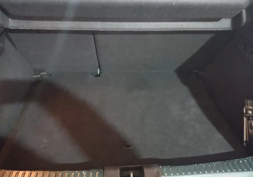 Coffre ouvert d'une Dacia Sandero Extreme+ vert, montrant l'espace de chargement vide et la banquette arrière rabattable.