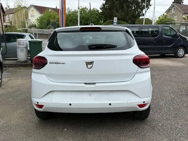 Vue arrière d'une Dacia Sandero blanc glacier 2023, avec feux arrière rouges et logo central visible.