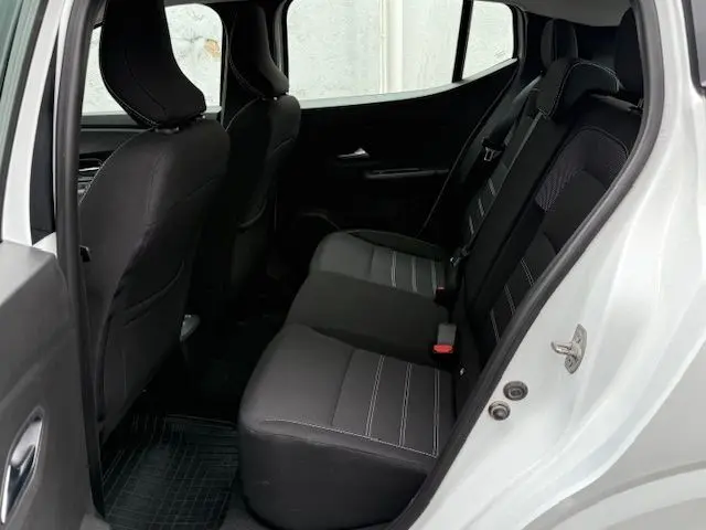 Vue intérieure côté droit des sièges arrière noirs d'une Dacia Sandero blanc glacier 2023 avec portière ouverte.
