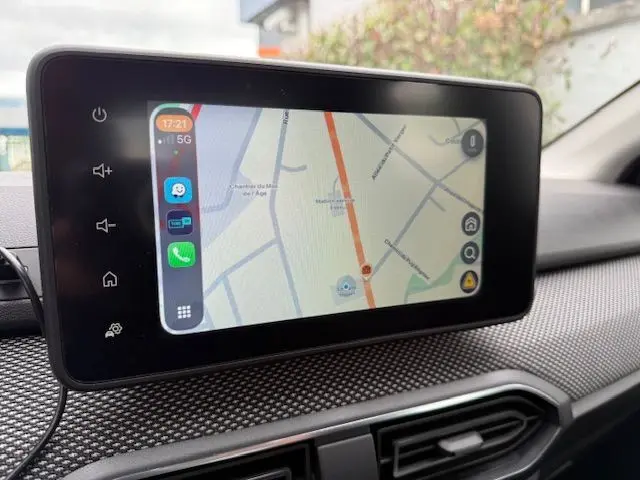 Écran tactile central affichant un GPS dans l’habitacle d’une Dacia Sandero blanche, vue rapprochée du tableau de bord.