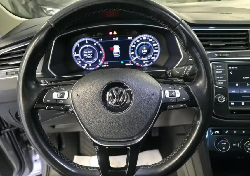 Vue intérieure centrée sur le volant cuir noir multifonctions et le combiné d'instruments digital du Volkswagen Tiguan gris 2016.