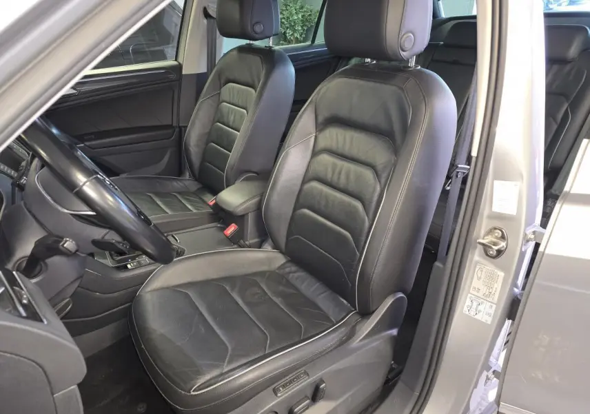 Vue intérieure côté conducteur du Volkswagen Tiguan gris 2016, sièges sport en cuir noir avec réglages électriques.