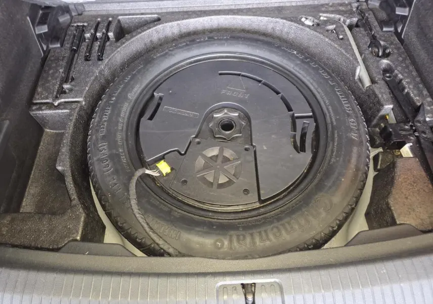Vue plongeante sur la roue de secours et l'outillage dans le coffre du Volkswagen Tiguan gris 2016.