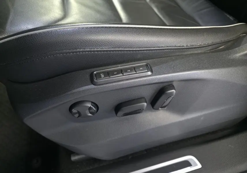 Détail des commandes électriques de réglage du siège conducteur en cuir noir du Volkswagen Tiguan gris 2016.
