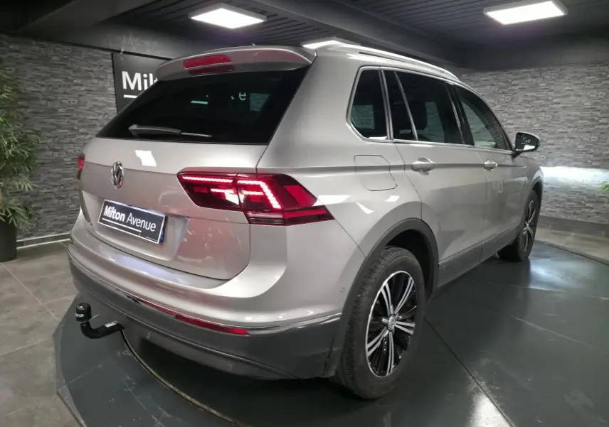 Vue 3/4 arrière droite d'un Volkswagen Tiguan gris avec jantes alliage noires et crochet d'attelage démontable.