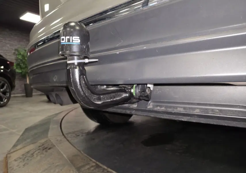 Gros plan sur le crochet d'attelage démontable à l'arrière d'un Volkswagen Tiguan gris 2016 en intérieur.