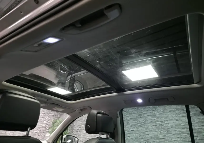 Vue intérieure du toit ouvrant panoramique et des sièges avant en cuir noir du Volkswagen Tiguan gris 2016.