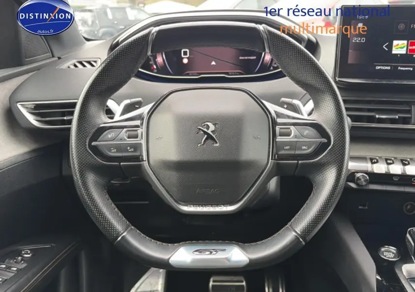 Vue rapprochée du volant cuir perforé Peugeot 3008 GT avec commandes multifonctions et logo GT au bas.