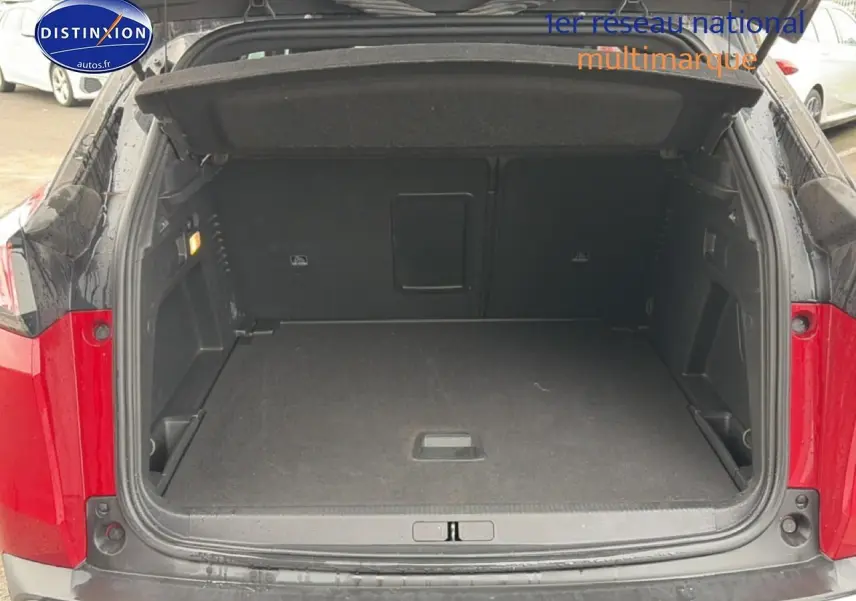 Coffre ouvert vu de l'arrière d'un Peugeot 3008 rouge, montrant l'espace de chargement vide et les finitions intérieures noires.