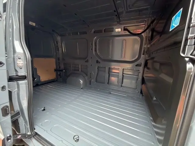 Vue intérieure arrière du Renault Master gris foncé, montrant l'espace de chargement vide et les parois métalliques.