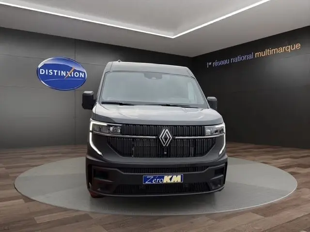 Vue avant d’un Renault Master gris foncé avec calandre noire verticale et feux LED en forme de C dans un showroom.