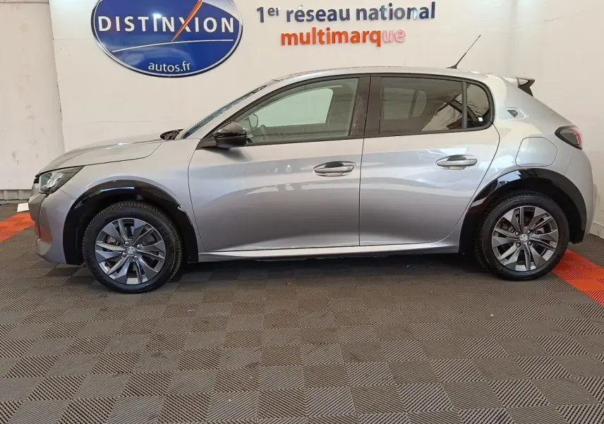Profil droit d'une Peugeot 208 Electrique Roadtrip gris clair, avec jantes alliage et protections noires sur les passages de roues.
