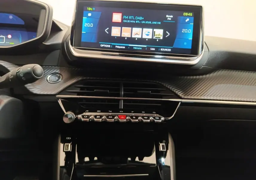 Vue rapprochée du tableau de bord de la Peugeot 208 Electrique Roadtrip 2022 avec écran tactile central allumé.
