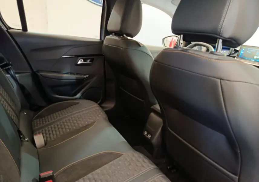 Vue intérieure arrière de la Peugeot 208 Electrique Roadtrip 2022, sièges noirs avec surpiqûres orange et ports USB au centre.