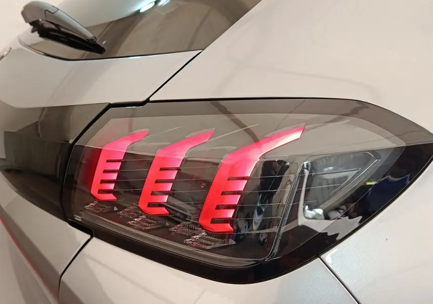 Gros plan sur le feu arrière droit rouge vif d'une Peugeot 208 électrique gris clair, finition Roadtrip 2022.