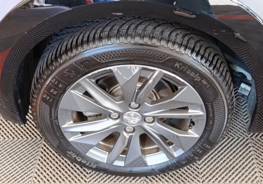 Gros plan sur la roue avant droite d'une Peugeot 208 électrique gris clair avec jante alliage à cinq branches.
