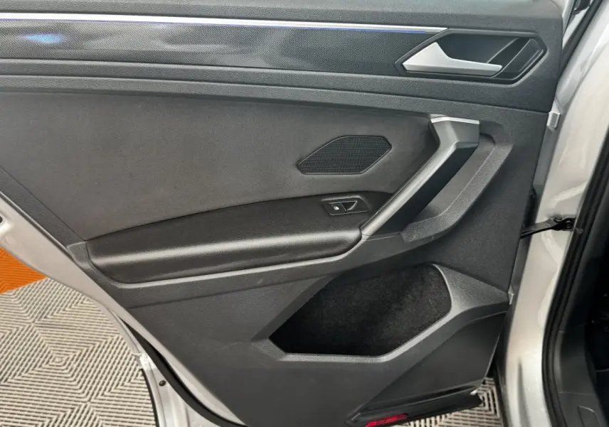 Vue rapprochée de la porte arrière droite gris clair du Volkswagen Tiguan 1.5 TSI 150 DSG7 Elegance avec poignée et haut-parleur intégrés.