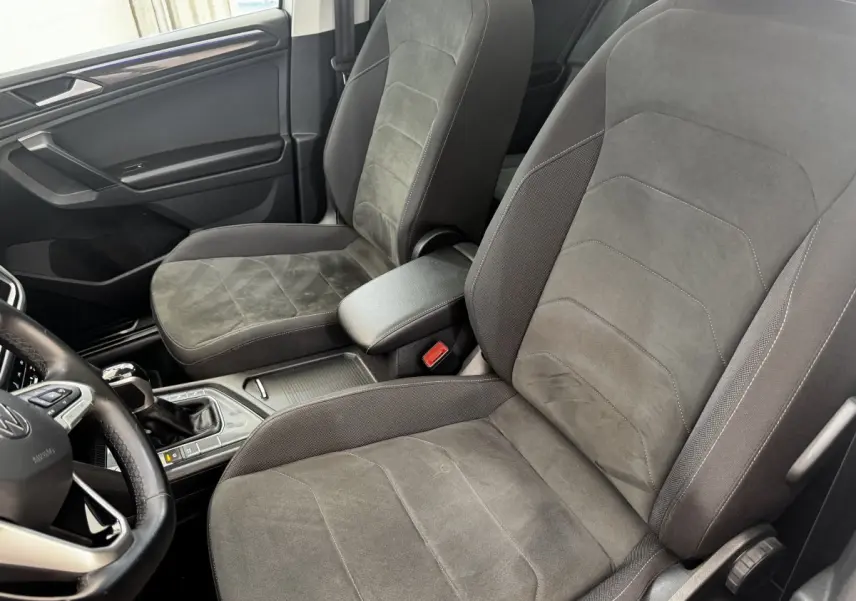 Vue intérieure côté conducteur du Volkswagen Tiguan gris, mettant en valeur les sièges tissu et alcantara et la console centrale.