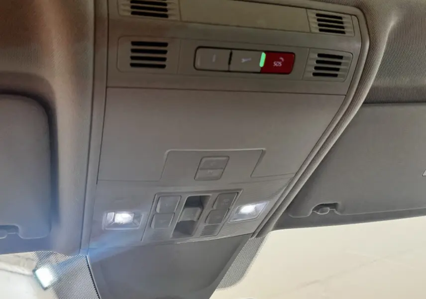 Plafonnier intérieur avec commandes d’éclairage et bouton SOS du Volkswagen Tiguan gris clair, vue en contre-plongée.