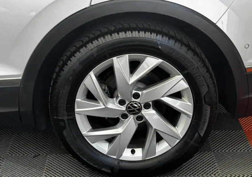 Gros plan sur la roue avant droite gris clair du Volkswagen Tiguan 1.5 TSI 150 DSG7 Elegance avec jante alliage moderne.