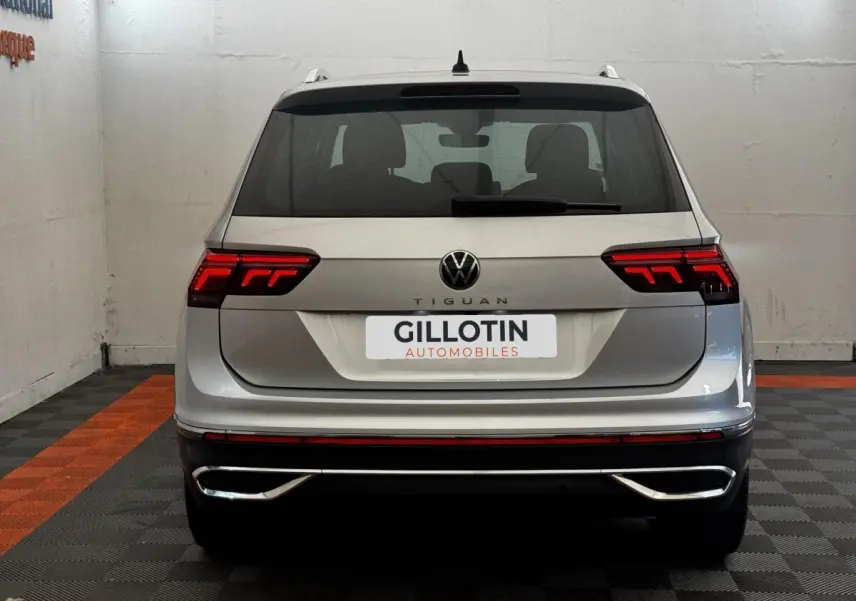 Vue arrière d'un Volkswagen Tiguan gris clair 2021 avec feux LED allumés et double sortie d'échappement chromée.