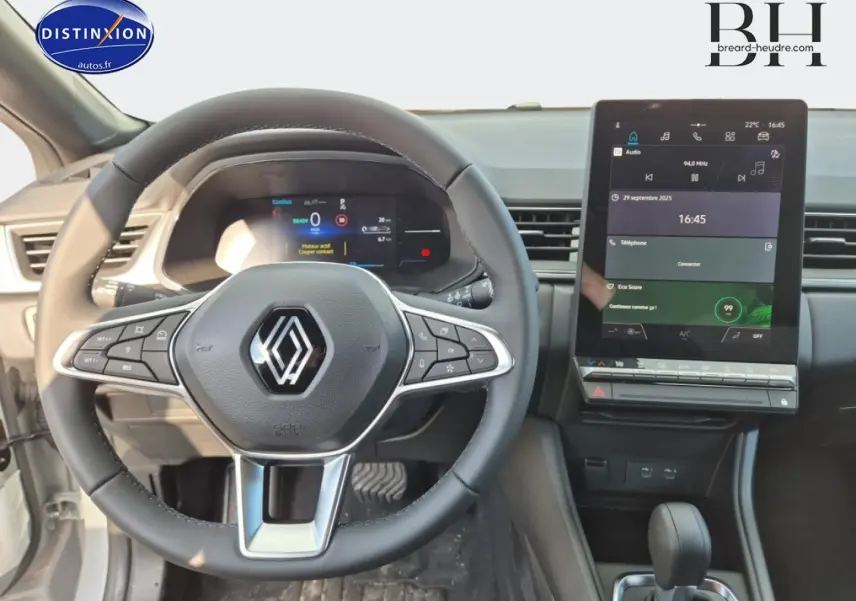 Vue intérieure centrée sur le volant Renault et l'écran tactile vertical du tableau de bord du Captur bleu Iron.