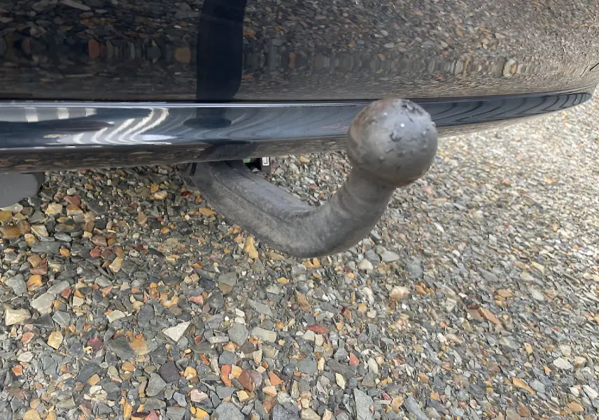 Gros plan sur l'attelage d'une Mercedes Classe E 320 CDI noire de 2003, vue arrière basse avec sol en gravier.