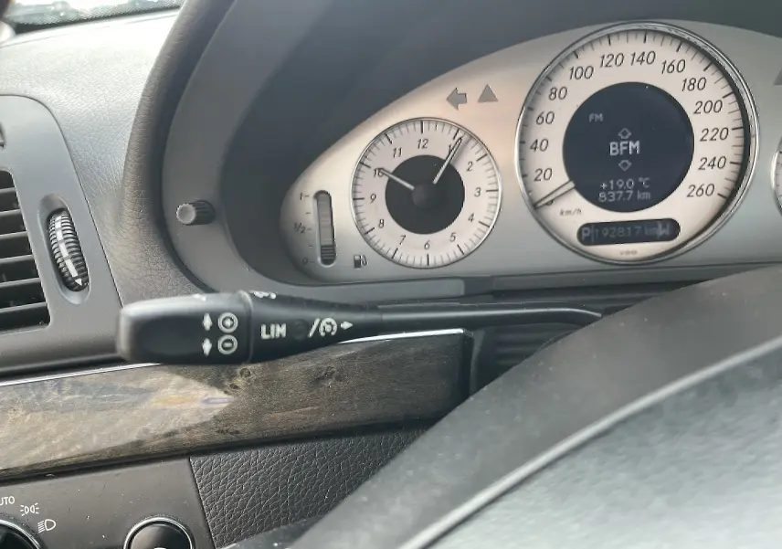 Gros plan sur le tableau de bord et compteur argenté d'une Mercedes Classe E 320 CDI noire de 2003, affichant 192817 km.