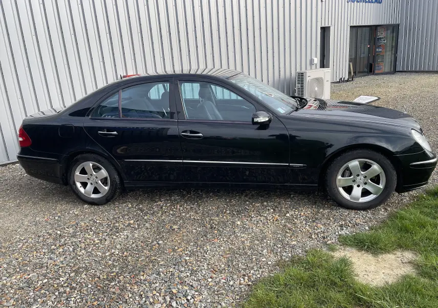 Profil côté gauche d'une Mercedes Classe E 320 CDI élégance noire de 2003, avec jantes alliage et carrosserie brillante.