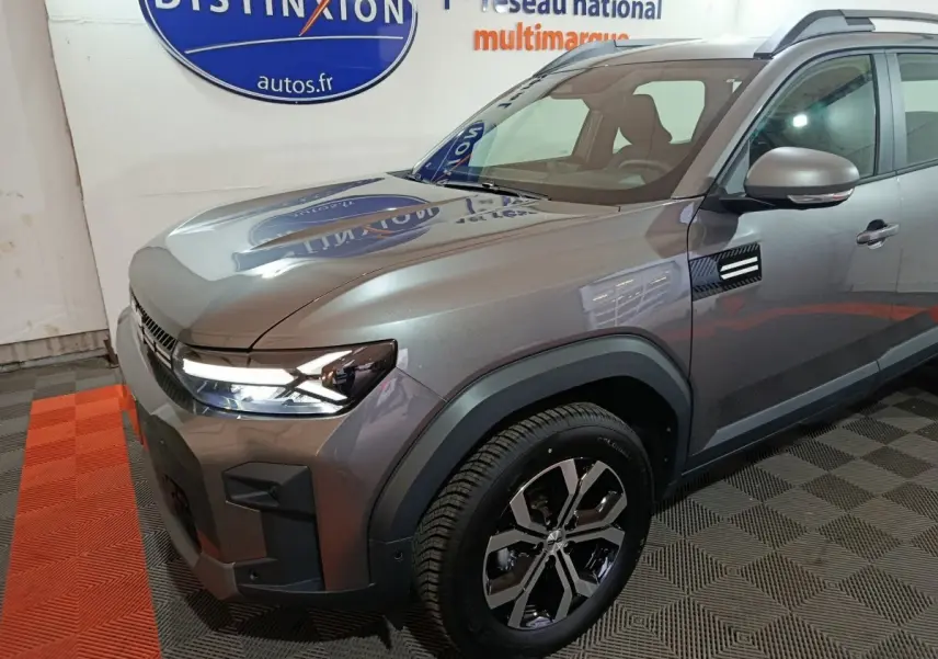 Vue 3/4 avant droit du Dacia Bigster gris foncé avec phares LED et jantes alliage au showroom Distinxion.