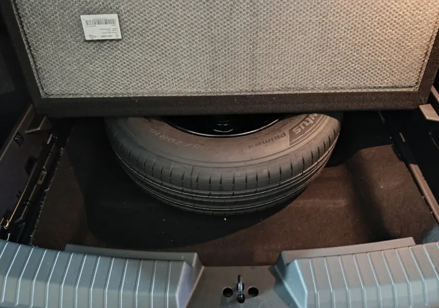 Vue plongeante sur la roue de secours dans le coffre du Dacia Bigster gris foncé, version mild hybrid 2025.