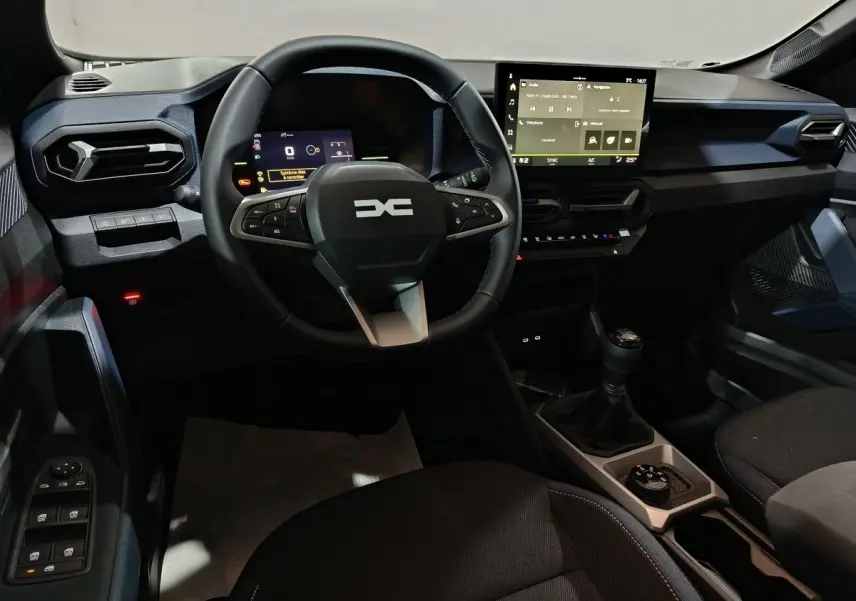 Vue intérieure du tableau de bord et volant du Dacia Bigster 2025, avec écran tactile central et levier de vitesses manuel.
