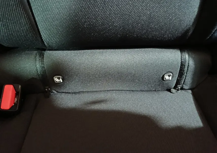 Gros plan sur la banquette arrière noire du Dacia Bigster avec attaches Isofix visibles et ceinture rouge partiellement montrée.