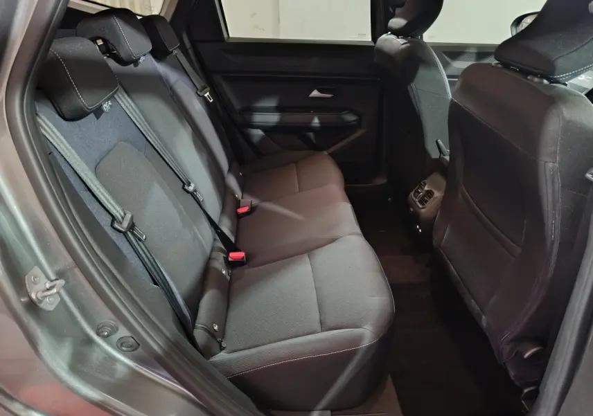Vue intérieure arrière côté gauche du Dacia Bigster gris foncé, montrant la banquette trois places en tissu noir.