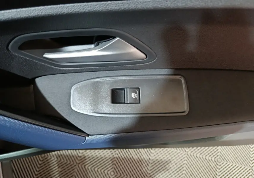 Gros plan sur la poignée intérieure et le bouton de verrouillage de la porte côté conducteur du Dacia Bigster gris foncé.