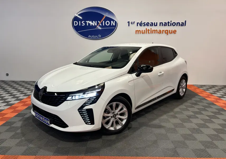 Renault Clio V blanche vue 3/4 avant droit avec feux LED allumés dans un showroom multimarque.