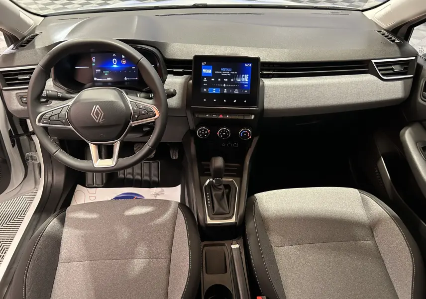 Vue intérieure avant de la Renault Clio V TCE 90ch, tableau de bord noir et gris avec écran tactile central et volant multifonction.