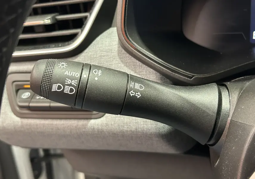 Gros plan sur la commande des feux et clignotants côté gauche du tableau de bord de la Renault Clio V blanche.