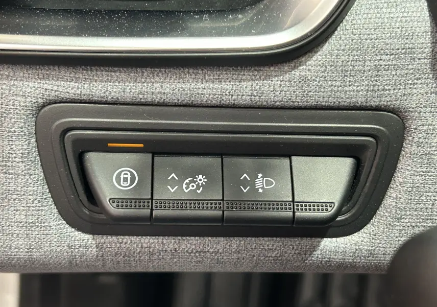 Gros plan sur les boutons de réglage d’éclairage et de verrouillage intérieur de la Renault Clio V blanche.