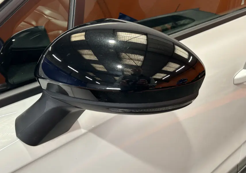 Rétroviseur extérieur noir côté gauche d’une Renault Clio V blanche, vue rapprochée sur la portière.