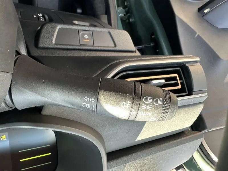 Gros plan sur la commande des feux et clignotants à gauche du volant dans l'habitacle du Dacia Jogger blanc.