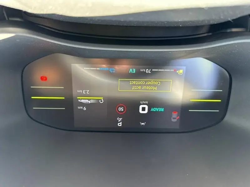 Vue rapprochée du tableau de bord numérique du Dacia Jogger blanc, affichant les alertes et la vitesse à 0 km/h.