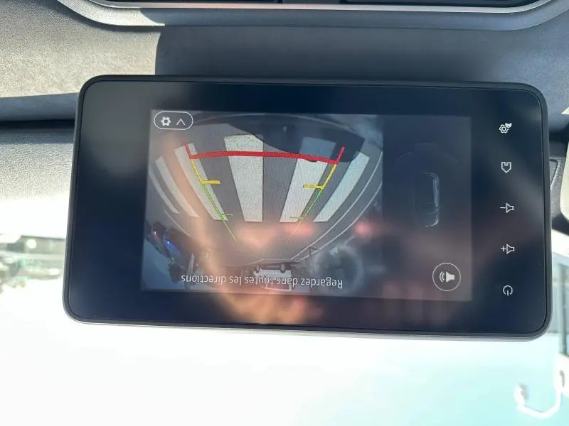 Écran tactile intérieur montrant la caméra de recul du Dacia Jogger blanc, avec lignes de guidage colorées.