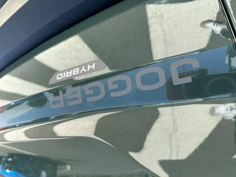 Gros plan sur l’inscription JOGGER et le badge HYBRID sur la carrosserie noire brillante du Dacia Jogger.