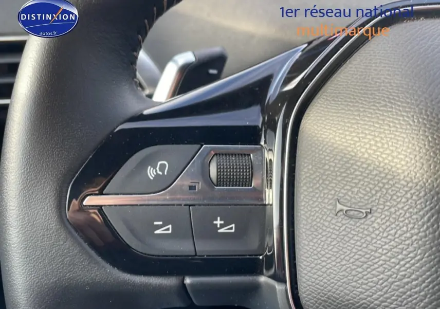 Gros plan sur les commandes vocales et volume au volant cuir noir du Peugeot 3008 bleu Plug-in Hybrid 2024.
