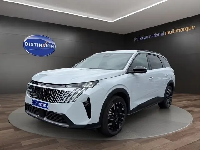 Peugeot 5008 blanc vue 3/4 avant droit en intérieur, avec calandre noire et jantes noires distinctives.